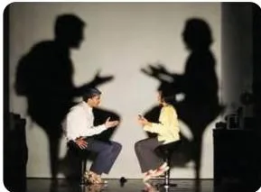 Actors moving in a play of shadows on stage, where light and shadow create mood and hidden meaning for the audience