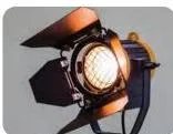 A PC spotlight fitted with four hinged barndoor flaps in front of the lens, used to shape the beam and stop spillage