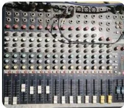A sound console covered in vertical channel strips of knobs and faders, the mixer that blends every microphone input
