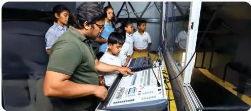 Students at an auditorium learning light and sound control from a technical professional during a field trip