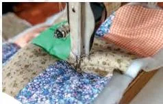 Hands sewing small fabric pieces together to make a patchwork from leftover cloth scraps