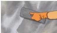 A worker applying a base coat of plaster to a brick wall with a trowel, smoothing it evenly before the second coat