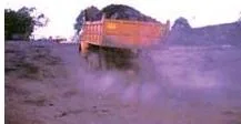 Dust rising from a mining area over machinery and piles of extracted rock, showing the air pollution that brings pulmonary diseases to miners