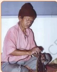 An instrument maker shaping a log of wood into the cylindrical body of a drum