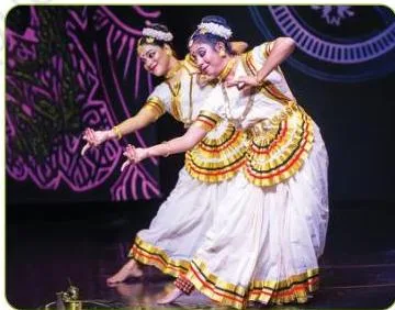 Mohiniyattam dancer in a white kasavu saree with a golden border, performing gentle upper-body movements of Kerala