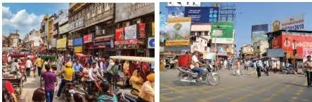Hoardings and signboards over shops in a busy Indian marketplace, advertising local businesses to people passing by