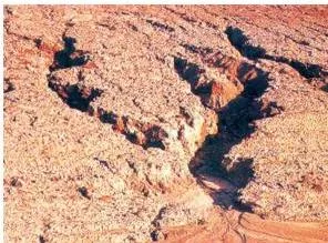 Photograph of deep gullies cut into clayey soil by running water, land that has become unfit for cultivation