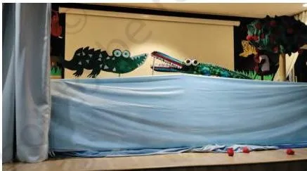 A bedsheet draped over a table as a puppet stage, hiding the puppeteer who works behind it