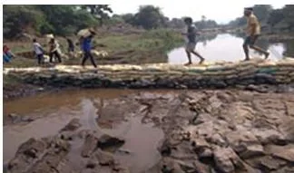 A small check dam built across a water stream slowing the runoff so that the water can be used for irrigating the surrounding fields