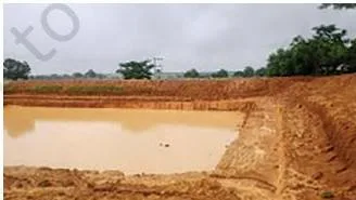 A percolation tank partly filled with rainwater, built so that water seeps slowly down into the ground to recharge groundwater
