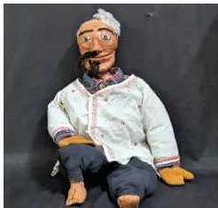 A finished stick puppet of Gopal from the sample script, with a painted face and a long dress covering the stick