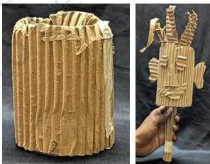 A puppet made from discarded cardboard with cut-out eyes, nose, mouth, ears and hair pasted on, and broomsticks inserted to move it