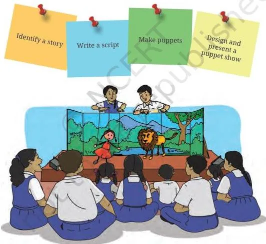 Students seated together watching a puppet show on a small stage, the audience a completed puppet project is performed for