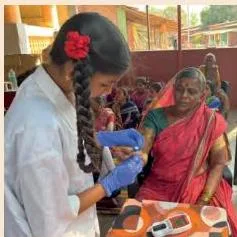 A student volunteer guiding a visitor through registration at a community health camp, showing the service flow that keeps visitors satisfied